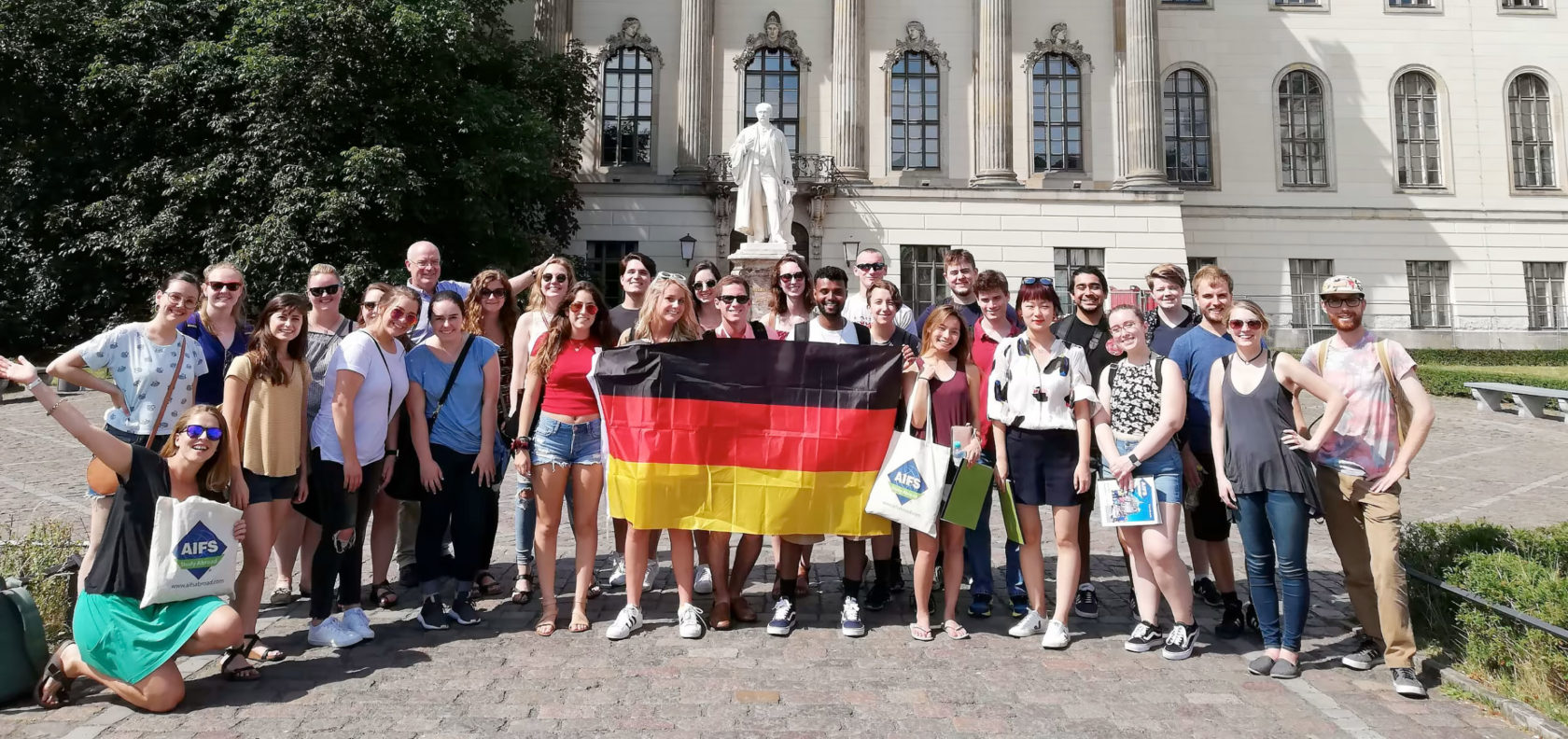A group of students holding a German flag in front of Humboldt University.